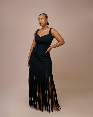 Woman wearing a black fringe dress against a beige background